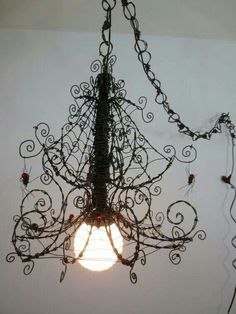 a chandelier hanging from the ceiling with vines and lightshades on it