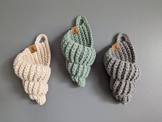 three crocheted baby mittens hanging on the wall, one in grey and one in green