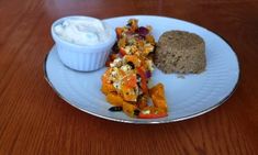 a white plate topped with food next to a bowl of ranch dressing on top of a wooden table