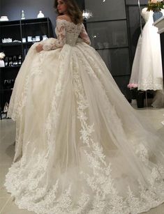 a woman in a wedding dress is looking at the gown on her mannequin