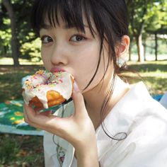 a woman eating a donut with sprinkles on it in the park