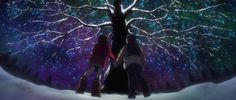 two people standing under a tree with the stars in the sky behind them and snow on the ground