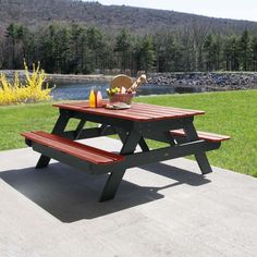 a picnic table in the middle of a grassy area with flowers and fruit on it