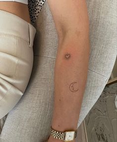 a woman's arm with a small sun and moon tattoo on her left arm