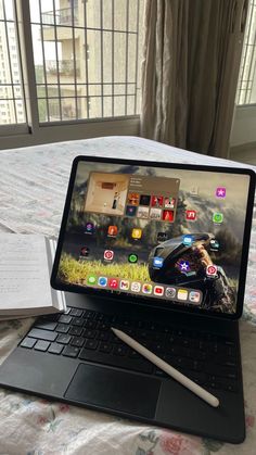 an open laptop computer sitting on top of a bed next to a notepad and pen