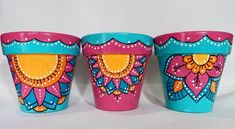 three colorful flower pots sitting next to each other