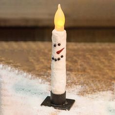 a snowman candle is sitting in the snow