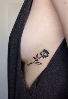 a small rose tattoo on the side of a woman's right breast is shown