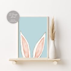 a white vase sitting on top of a wooden shelf next to a blue wall with an image of two bunny ears