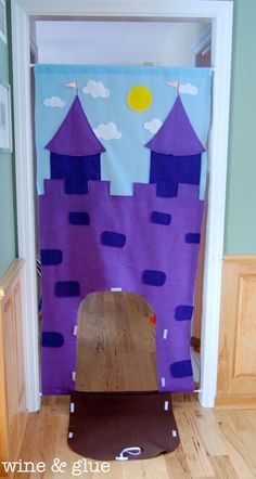 a purple castle made out of cardboard sitting on top of a hard wood floor next to a door