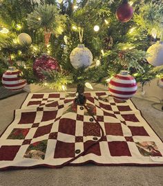 a christmas tree with ornaments on it and a checkerboard table runner in the foreground