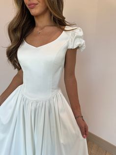 a woman in a white dress posing for the camera