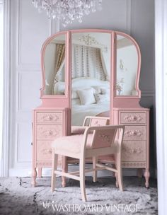 a pink dressing table with a mirror and chair