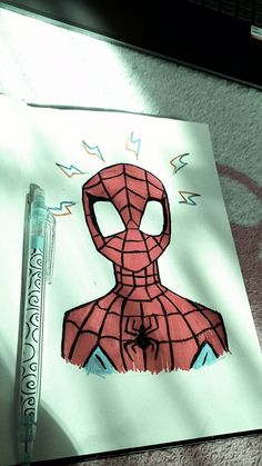 a drawing of a spider man on paper next to a marker