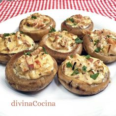 a white plate topped with stuffed mushrooms on top of a red and white checkered table cloth