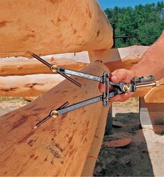 a man is holding two pliers over a piece of wood that has been cut in half