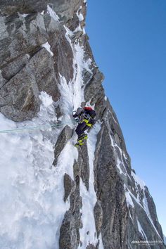 a man on skis climbing up the side of a mountain