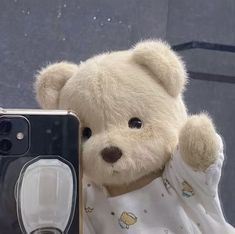 a white teddy bear holding up a camera