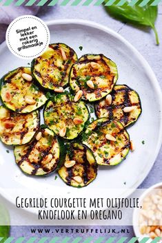 grilled zucchini with pine nuts on a white plate