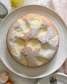 a white plate topped with a cake covered in powdered sugar on top of a table