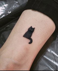 a small black cat tattoo on the ankle