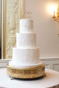 a white wedding cake sitting on top of a round table next to a gold plate