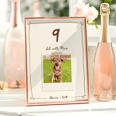 a photo frame with a dog on it and a bottle of champagne in the background