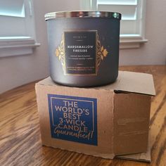 a candle sitting on top of a cardboard box next to a window with the words, the world's best 3 - wick candle