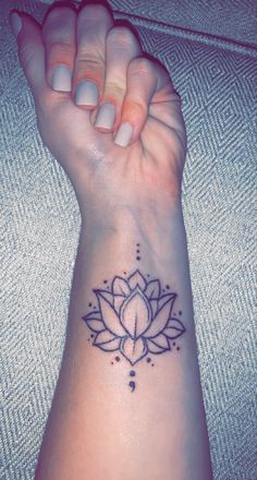 a woman's wrist tattoo with a lotus flower on the left side of her arm