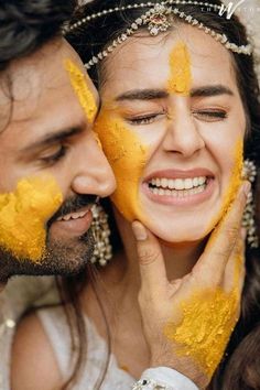 a man and woman with yellow paint on their faces smiling at each other's eyes