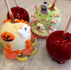 three decorated apples sitting on top of a table next to an apple and candy bar