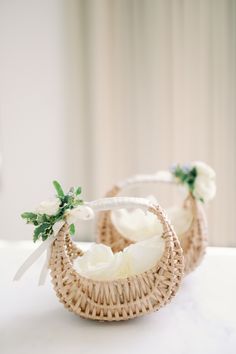 two wicker baskets with flowers on them sitting on a white countertop in front of a window