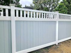 a white picket fence in front of some trees