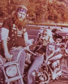 a man sitting on top of a motorcycle next to another man with a long beard