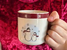 a person holding a coffee cup with two snowmen on it