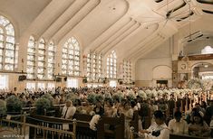 a large group of people sitting in pews inside of a church with stained glass windows