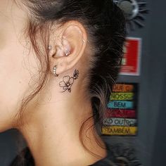 a woman with a flower tattoo on her left ear and behind her ear is a stack of books