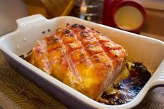 a casserole dish with meat and vegetables in it on a table next to a cup