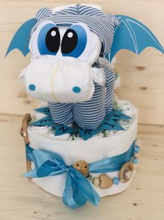 a diaper cake with a stuffed dragon on top and blue ribbon around the edge