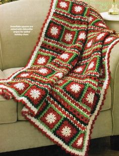 a crocheted blanket is sitting on a couch in front of a christmas tree