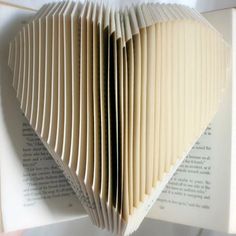 an open book with folded pages in the shape of a heart