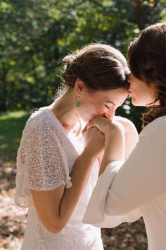 two women in white dresses standing next to each other with their hands on their chests