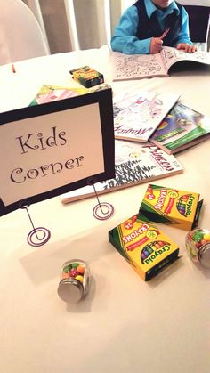 a young boy sitting at a table with some candy in front of him and a sign that says kids corner