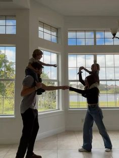 three people standing in front of large windows holding onto one another's arms with their hands