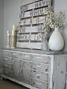 an old dresser has been decorated with white flowers and wooden pallets for the top