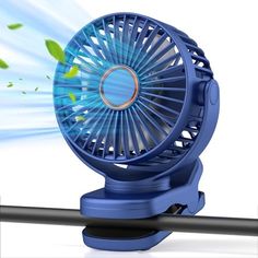 a blue fan sitting on top of a metal pole next to a green leafy plant