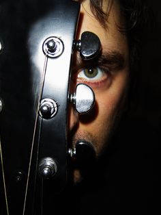 a close up of a person with an electric guitar in front of their face and eyes