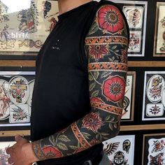 a man standing in front of a wall with tattoos on his arms and arm,