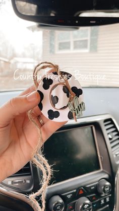 a person is holding up a cow ornament in their car's dashboard