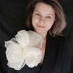 a woman wearing a black jacket holding a white flower